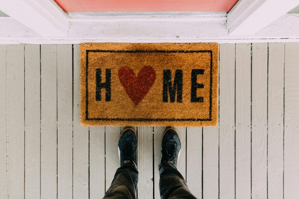 Blog A creative doormat with heart motif symbolizing home at a front porch entrance.